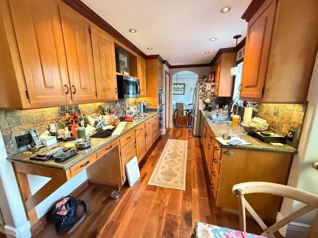 Galley kitchen before remodeling with wood cabinets and dark tile backsplash