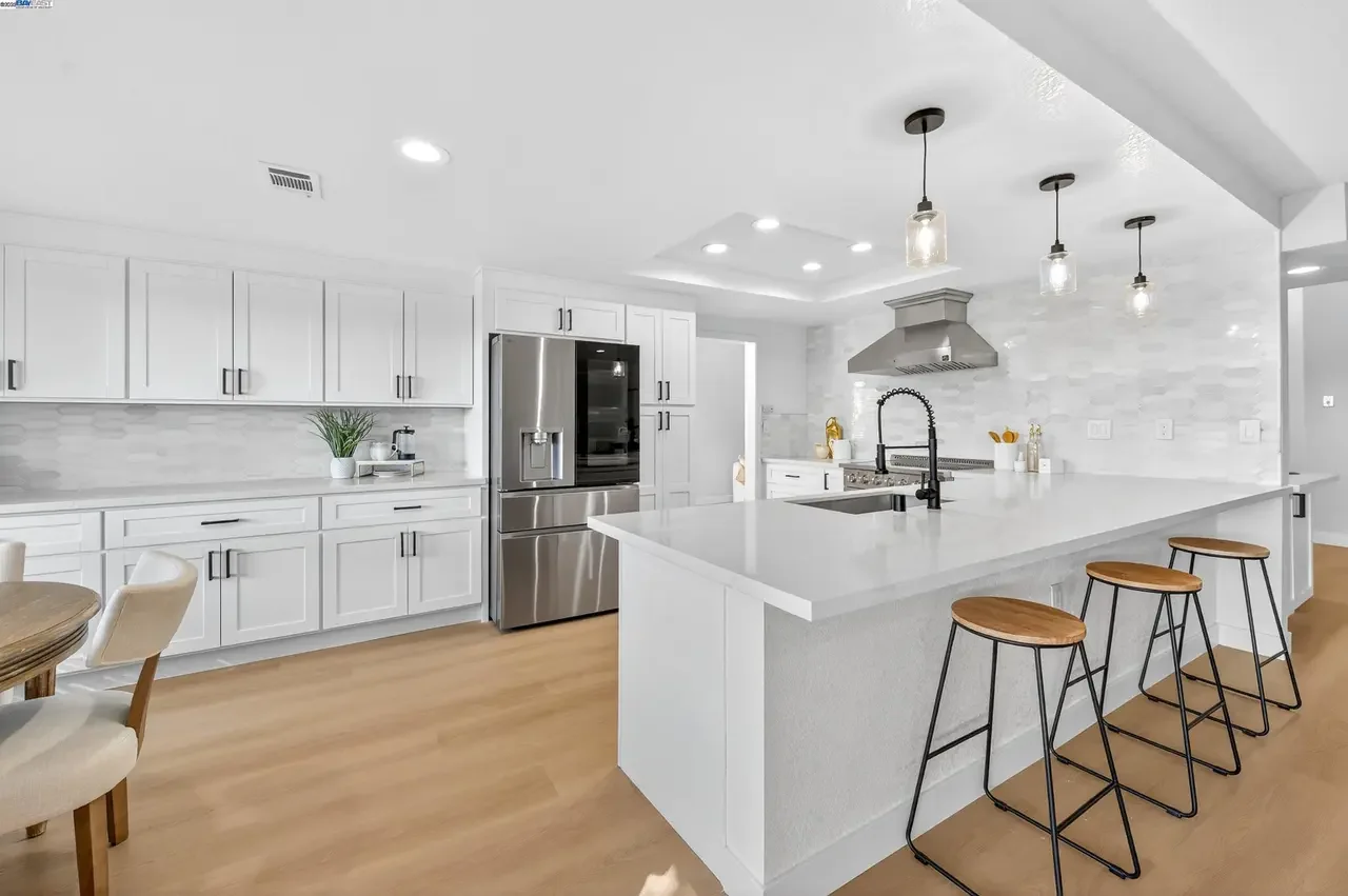 Kitchen after remodeling with white cabinets, quartz island and pendant lights